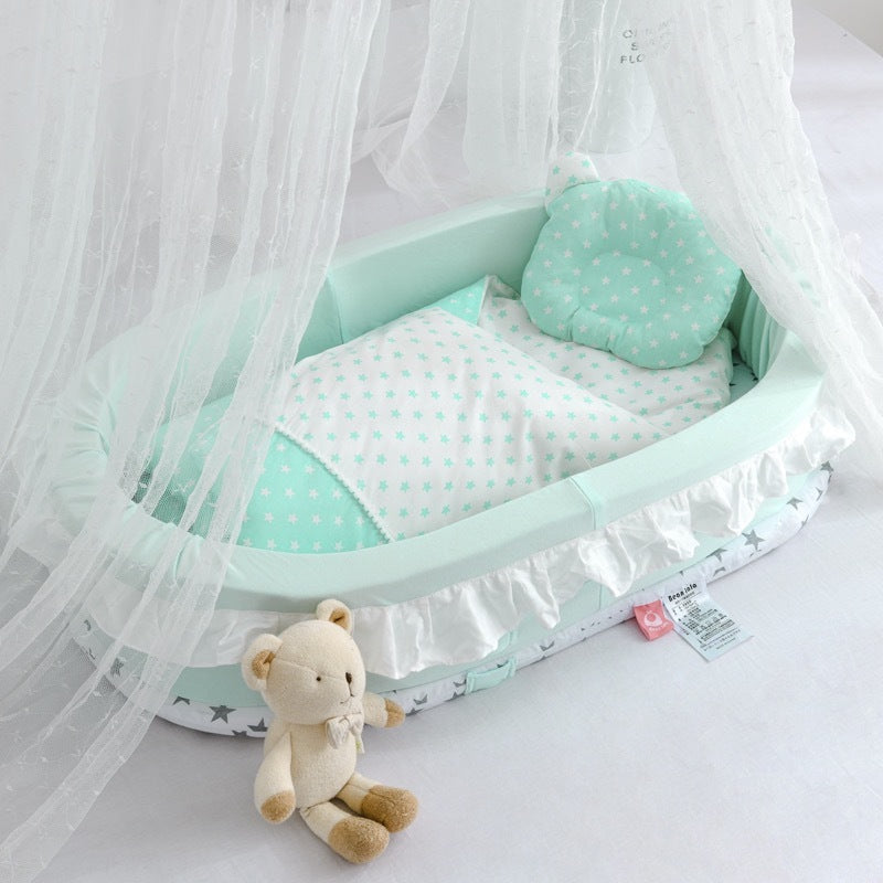 Mint green baby crib with white polka dot bedding and a teddy bear toy on a light gray background.